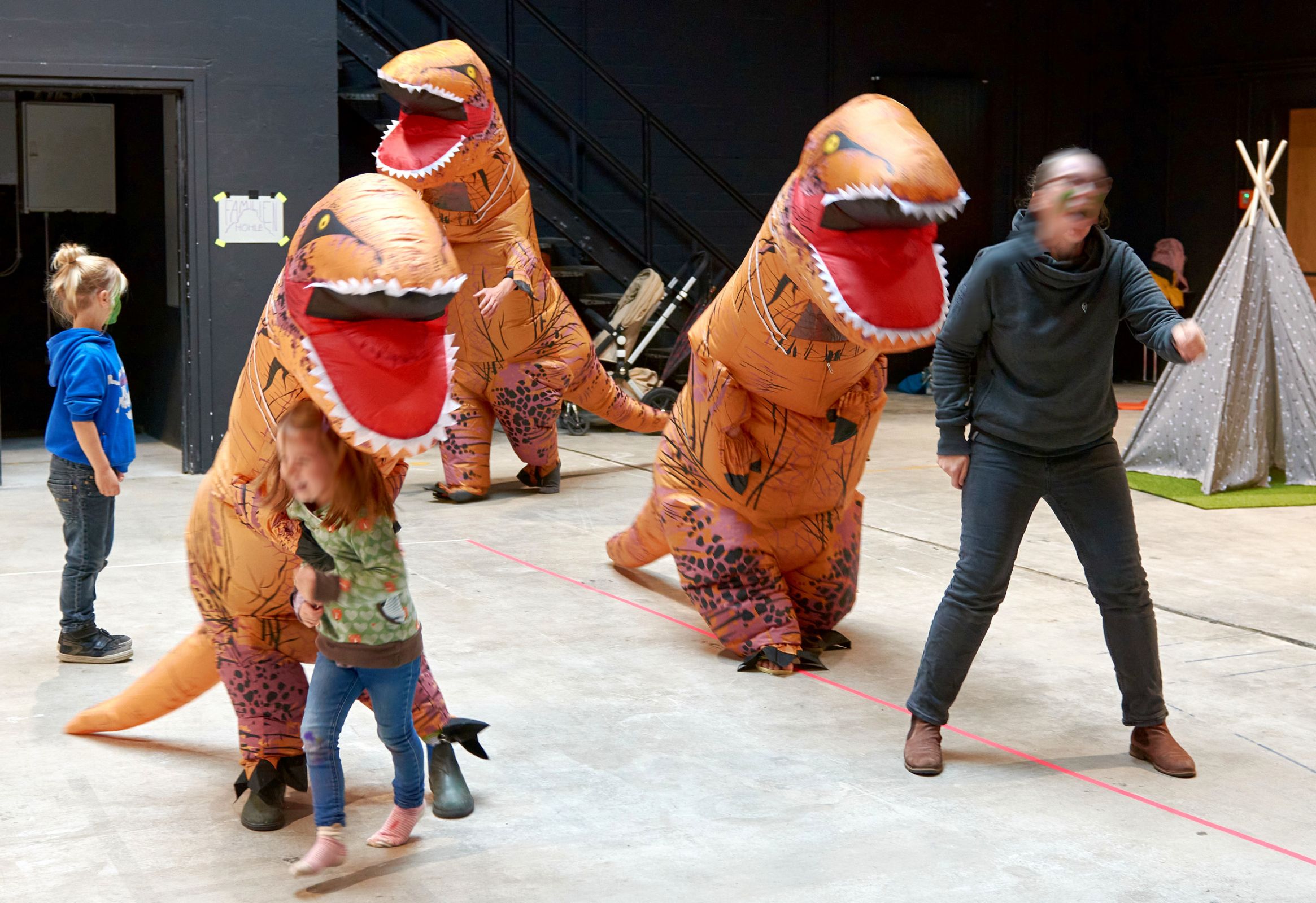 Darsteller mit Dinosaurierkostümen jagen Zuschauerinnen
